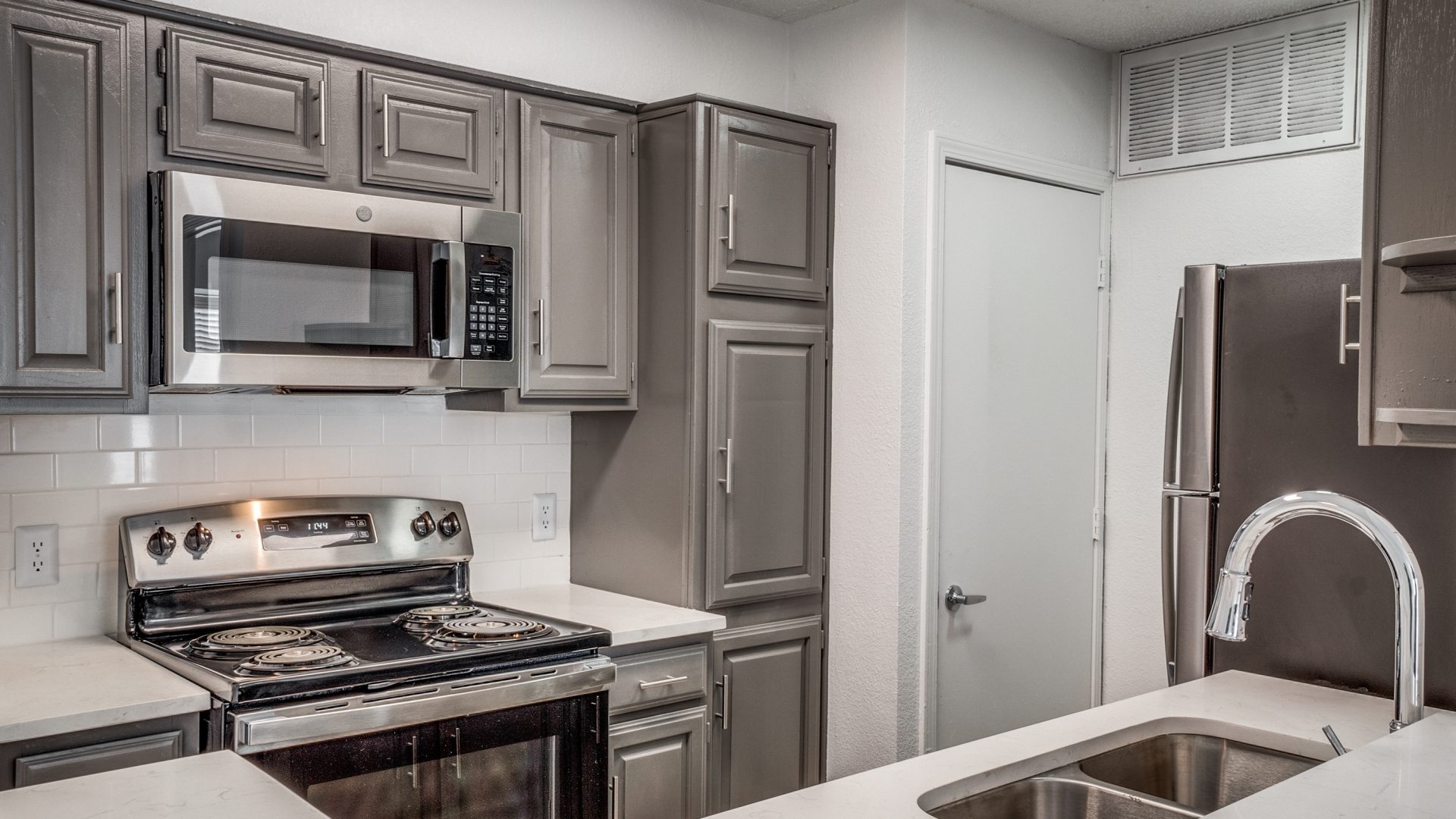 a kitchen with stainless steel appliances and gray cabinets at The  Laney