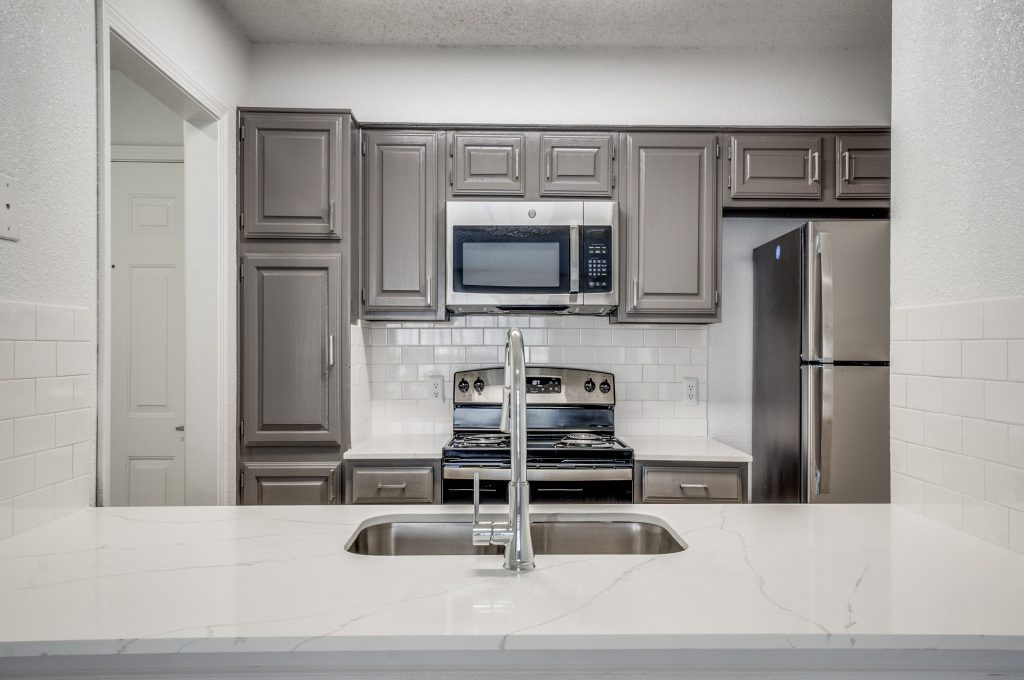 a kitchen with stainless steel appliances and gray cabinets at The  Laney